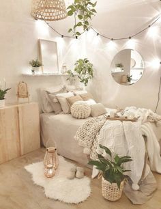 a bedroom decorated in white with plants and lights