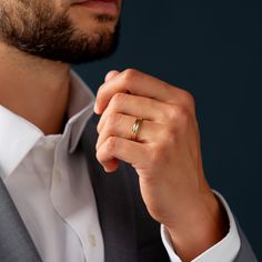 a man in a suit is holding onto his wedding band and wearing a gold ring