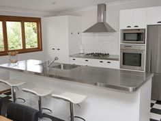 a modern kitchen with stainless steel appliances and black and white checkered flooring on the walls