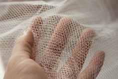 a woman's hand is touching the net on her bed