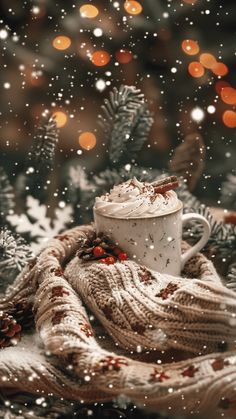 a cup of hot chocolate on a blanket in front of a christmas tree with lights