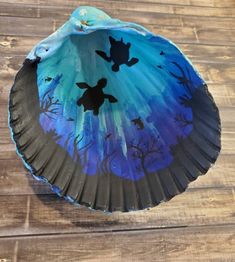 a paper plate with blue and black designs on the bottom, sitting on a wooden surface