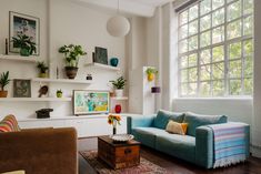 a living room filled with furniture next to a window covered in plants and potted plants