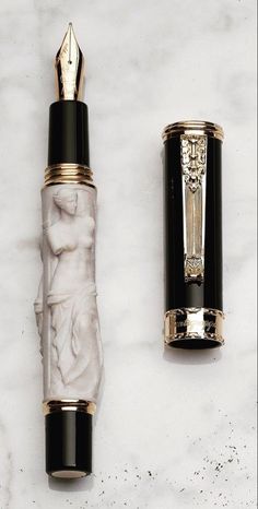 a fountain pen with a marble design and gold trim, next to it is a black nib