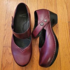 Elevate your style with these Dansko Mary Jane wedges. Crafted from durable leather, they offer both comfort and elegance. Ideal for daily wear. * Burgundy leather upper * Mary Jane strap with button detail * Cushioned insole for comfort * Wedge heel design * Size 41 (US Equivalent 10.5/11) Size: Womens 10.5 Measurements taken with item laid flat and are approx. Heel Height 2 in Marks and wear as shown.  Comfort Orthotic Plantar Fasciitis Comfy Comfortable Clog mule coastal grandmother coastal grandma normcore Academia Granny Grannycore Grandmacore Librarian Secretary Geek Nerd Nerdy Twee Preppy casual artsy Boho Hippie Chic Neutral Bohemian Festival Coachella Burning Man Rave Festivals Cottagecore Prairie Minimalist Sustainable Comfortable Leather Heels With Arch Support, Comfortable Leather Heels With Round Toe, Leather Clogs With Low Heel, Comfortable Closed Toe Leather Heels, Comfortable Leather Heels With Rubber Sole, Leather Round Toe Heels With Arch Support, Leather Heels With Arch Support And Round Toe, Leather Closed Toe Clogs For Fall, Fall Leather Closed Toe Clogs