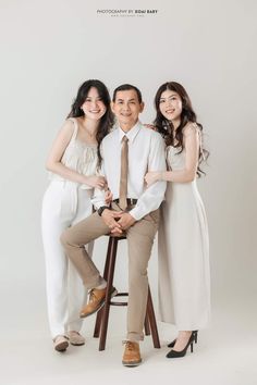 two women and a man posing for a photo together in front of a white background