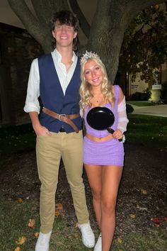 a man and woman dressed up in costumes posing for the camera with a tree behind them