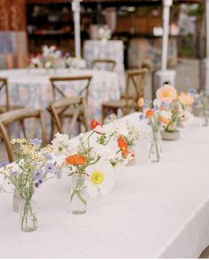 several vases filled with flowers sitting on top of a white tablecloth covered table