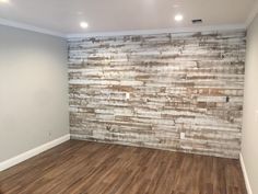 an empty room with hard wood flooring and white paint on the brick wall behind it