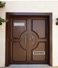 the front door to a building with two large doors and numbers on each one side