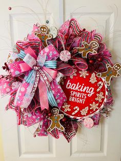 a pink and red wreath with the words baking starts right next to it on a door