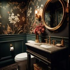 a bathroom with green walls and floral wallpaper on the walls, along with a gold framed mirror