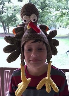 a young boy wearing a knit turkey hat