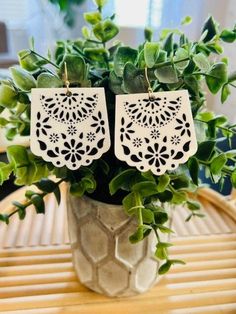 white laser cut earrings with green leaves in a vase