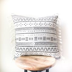 a black and white pillow sitting on top of a wooden stool