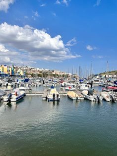 many boats are docked in the water near some buildings and blue sky with white clouds