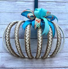 a blue and white bow on top of a rope ball hanging from a wooden wall