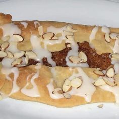 two pieces of bread with white icing and nuts on it sitting on a plate