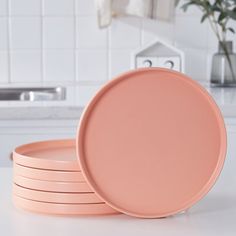 four pink plates stacked on top of each other in a kitchen with white counter tops