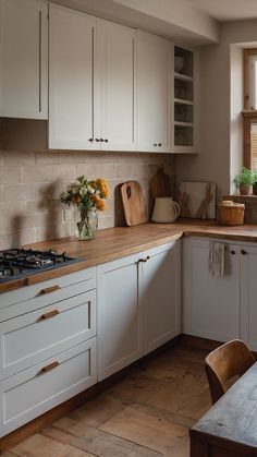 a kitchen with white cabinets and wooden counter tops next to a window filled with potted plants