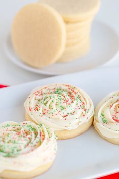 some cookies are sitting on a plate with white frosting and sprinkles