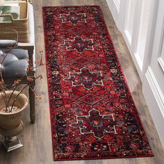 a large red rug on the floor next to a potted plant