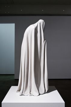 a white sculpture is on display in an empty room