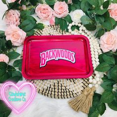 a tray with the word backwoods on it surrounded by pink roses and greenery