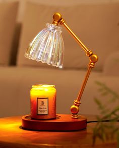 a table with a lit candle on it and a lamp next to it in front of a couch