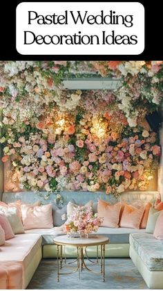 A pastel wedding lounge with a floral wall of pink, peach, and white blooms paired with soft blue and blush seating, plush pastel cushions, and a gold round table adorned with a pink flower centerpiece, showcasing pastel wedding decoration ideas for a cozy and elegant reception space.