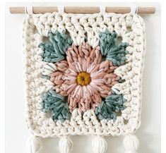 a crocheted wall hanging with tassels and flowers on the front side