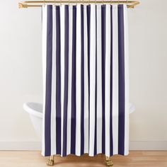 a blue and white striped shower curtain hanging on a gold metal rod in front of a bathtub