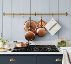 pots and pans are hanging on the wall above an oven