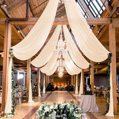 an indoor wedding venue with white draping and greenery