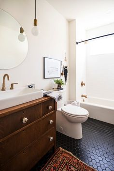 a white toilet sitting next to a bath tub in a bathroom under a large mirror