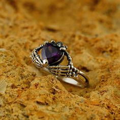 a ring with a purple stone in the middle on top of some rocks and dirt