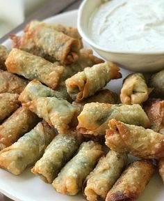 a white plate topped with fried food next to a bowl of ranch dressing and dipping sauce