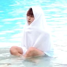 a woman sitting in the water wearing a white robe