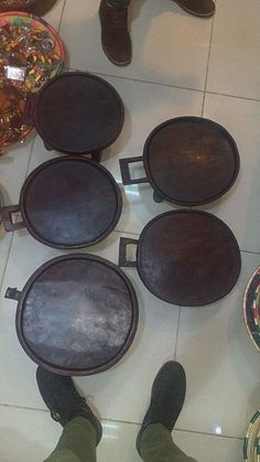 a person standing in front of several wooden trays on the floor with their feet propped up