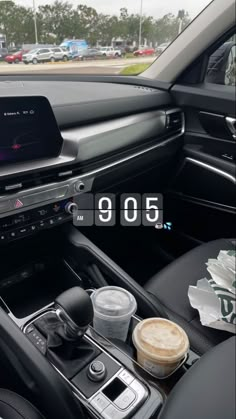 an image of the interior of a car with coffee and other items in it's center console