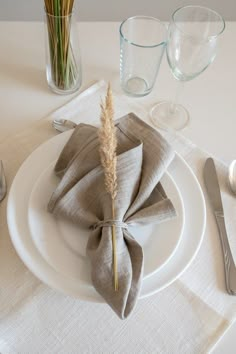 a place setting with napkins, silverware and flowers in glass vase on the table