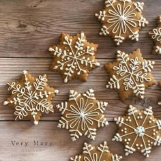 some very pretty decorated cookies on a wooden table with snowflakes in the middle