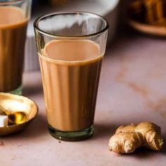 two glasses filled with liquid next to some ginger slices