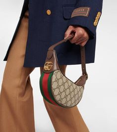 The '90s are firmly back on the fashion map with the Ophidia GG Mini shoulder bag from Gucci. The compact hemispherical style sits neatly under the arm from a short shoulder drop, and sports the label's iconic GG supreme canvas and web striped border. Brown leather trims and golden GG hardware completes the elegant design..Closure: zipped top.Color of fastening: gold.Comes with dust bag.Internal details: card slot, suede lining.Made in Italy.Material: polyester, polyurethane.Top handle.Trim: cal Gucci Ophidia, Brown Leather Bag, Gucci Shoulder Bag, Pretty Bags, Mini Shoulder Bag, Free Bag, Women's Bags, Shoulder Bag Women, Leather Trims