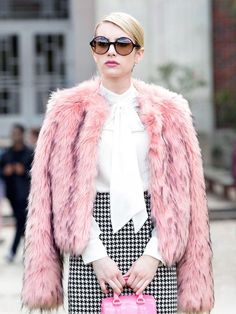 a woman in a pink fur coat holding a pink handbag with the words chanel on it