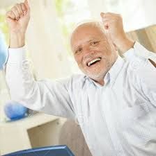 an older man raising his fist up in the air while sitting at a computer desk