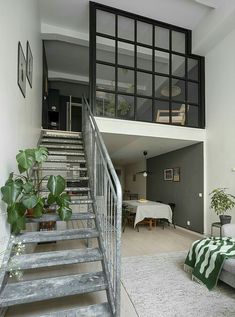 a living room with stairs leading up to the top floor and dining table in the background