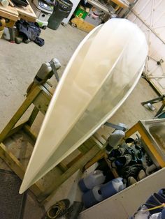 a large white boat sitting inside of a garage next to other tools and materials on the floor