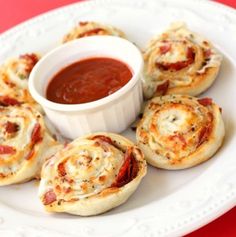 several small pizzas on a plate with sauce in a bowl next to the bread