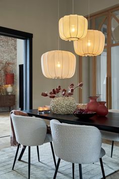 a dining room table with chairs and lights hanging from it